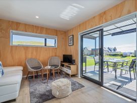 A living room with a sofa, chairs, and television at Opito Bay Holiday Home in Opito Bay