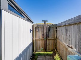 An outdoor shower area with a fence and shed at Opito Bay Holiday Home in Opito Bay