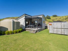 A house with a water tank and deck at Opito Bay Holiday Home in Opito Bay