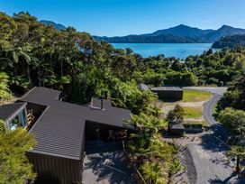 An aerial view of a house with trees and mountains at Nature's Luxe - Moetapu Bay Holiday Home Picton