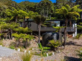 A house with a deck and water tank surrounded by trees at Nature's Luxe - Moetapu Bay Holiday Home in Picton