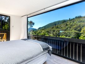 A bedroom with a bed and large window at Nature's Luxe - Moetapu Bay Holiday Home, Picton