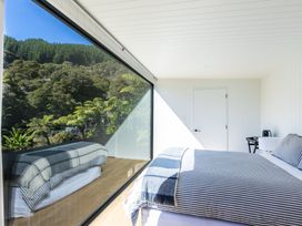 A bedroom with a bed and a large window at Nature's Luxe - Moetapu Bay Holiday Home Picton