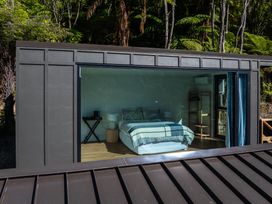 A bedroom with a bed and bedside table at Nature's Luxe - Moetapu Bay Holiday Home in Picton