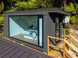 A bedroom with a bed and chair at Nature's Luxe - Moetapu Bay Holiday Home Picton