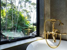 A bathroom with a bathtub and a gold faucet at Nature's Luxe - Moetapu Bay Holiday Home in Picton
