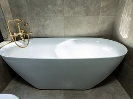 A bathtub with a faucet in a bathroom at Nature's Luxe - Moetapu Bay Holiday Home in Picton