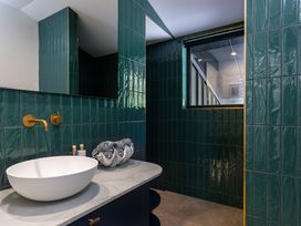 A bathroom with a sink and green wall tiles at Nature's Luxe - Moetapu Bay Holiday Home, Picton