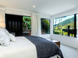 A bedroom with a bed and windows at Nature's Luxe - Moetapu Bay Holiday Home in Picton