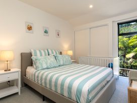 A bedroom with a bed and a crib at Nature's Luxe - Moetapu Bay Holiday Home, Picton