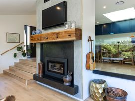 A living room with a fireplace, television, and guitar at Nature's Luxe - Moetapu Bay Holiday Home, Picton
