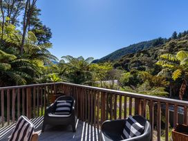 A deck with chairs and surrounding greenery at Nature's Luxe - Moetapu Bay Holiday Home in Picton