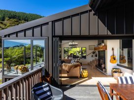 A living room with a sofa and guitar at Nature's Luxe - Moetapu Bay Holiday Home Picton