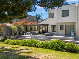 A house with a deck and outdoor furniture at Mount Maunganui