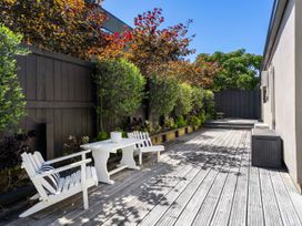An outdoor area with a wooden deck, table, and chairs at Mount Maunganui