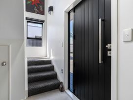 An entryway with stairs and a black front door at Mount Maunganui