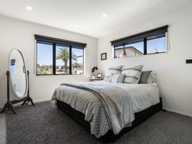 A bedroom with a bed and a mirror at Mount Maunganui