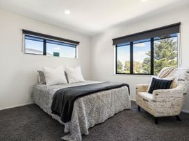 A bedroom with a bed and a chair at Mount Maunganui