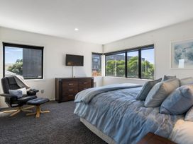 A bedroom with a bed, dresser, television and seating at Mount Maunganui