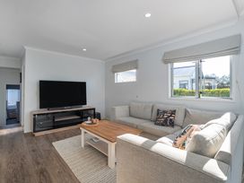 A living room with a sofa and television at Ocean Haven - Whangamata Holiday home in Whangamata