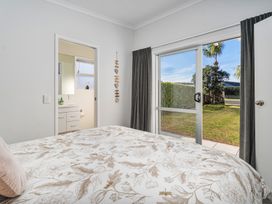 A bedroom with a bed and door leading to the outdoors at Ocean Haven - Whangamata