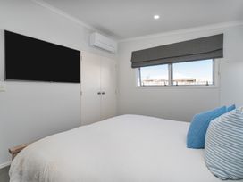 A bedroom with a bed and a television at Ocean Haven - Whangamata Holiday home in Whangamata