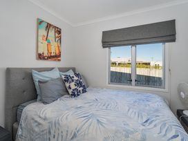 A bedroom with a bed and a painting at Ocean Haven - Whangamata Holiday home, Whangamata