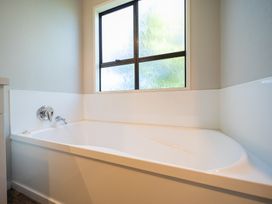 A bathtub beside a window at Four Peaks Matai Escape - Te Anau Holiday Home