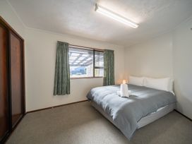 A bedroom with a bed and window at Four Peaks Matai Escape - Te Anau