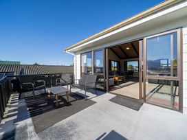A deck with chairs and a table at Four Peaks Matai Escape - Te Anau