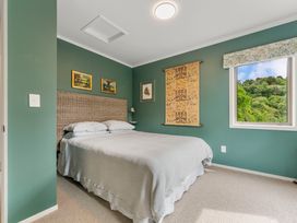 A bedroom with a bed, nightstand, and window at Camelot - Lake Taupo Holiday Home in Turangi