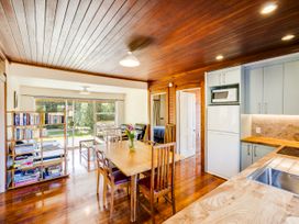 A kitchen with a table and chairs and a bookshelf at Pacific Vista - Hawkes Bay, Havelock North