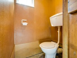 A bathroom with a toilet and window at Pacific Vista - Hawkes Bay Havelock North