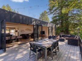 Outdoor patio with a dining table and sofa at Modern Coastal Tree House - Whangamata