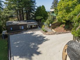 A house with a concrete driveway and trees at Modern Coastal Tree House - Whangamata Retreat, Whangamata