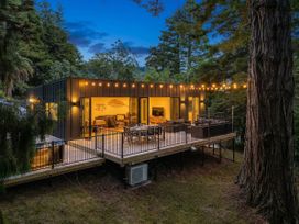 An outdoor area with a deck, table and chairs at Modern Coastal Tree House - Whangamata