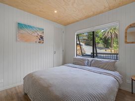 A bedroom with a bed and window at Modern Coastal Tree House - Whangamata Retreat, Whangamata