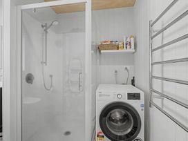 A bathroom with a shower and washing machine at Modern Coastal Tree House - Whangamata