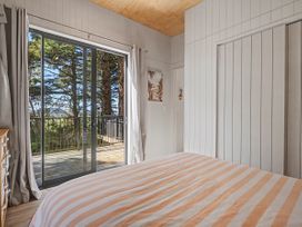 A bedroom with sliding doors and a bed at Modern Coastal Tree House - Whangamata Retreat, Whangamata