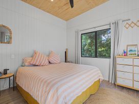 A bedroom with a bed and window at Modern Coastal Tree House - Whangamata Retreat in Whangamata