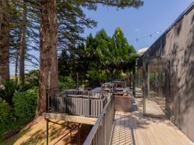 An outdoor deck with furniture and trees at Modern Coastal Tree House - Whangamata