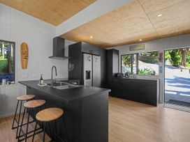 A kitchen with black cabinetry and a sink at Modern Coastal Tree House - Whangamata Retreat