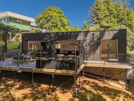 A house with a deck and trees at Modern Coastal Tree House - Whangamata Retreat Whangamata