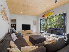 A living room with a sofa and television at Modern Coastal Tree House - Whangamata Retreat in Whangamata