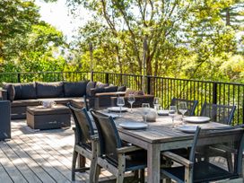 An outdoor space with a dining table and sofa at Modern Coastal Tree House - Whangamata
