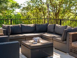 An outdoor seating area with a sectional sofa and coffee table at Modern Coastal Tree House - Whangamata