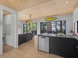 A kitchen area with a sofa and sliding doors at Modern Coastal Tree House - Whangamata Retreat in Whangamata