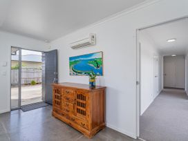 A hallway with a console cabinet and painting at Sweet As on Aquila - Whitianga Holiday Home