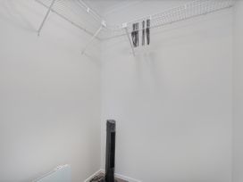 A laundry room with a shelf, clothes rack and floor fan at Sweet As on Aquila - Whitianga Holiday Home