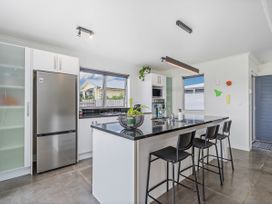 A kitchen with a fridge, countertop, and stools at Sweet As on Aquila - Whitianga
